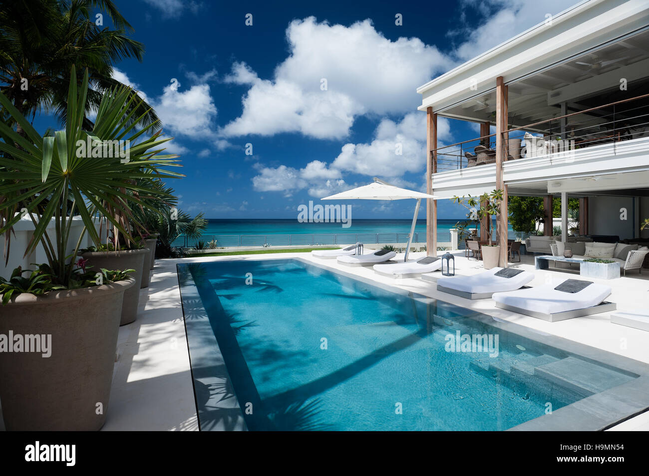 Tumbonas junto a la piscina en un alojamiento de lujo con vista al mar Caribe, West Indies Foto de stock
