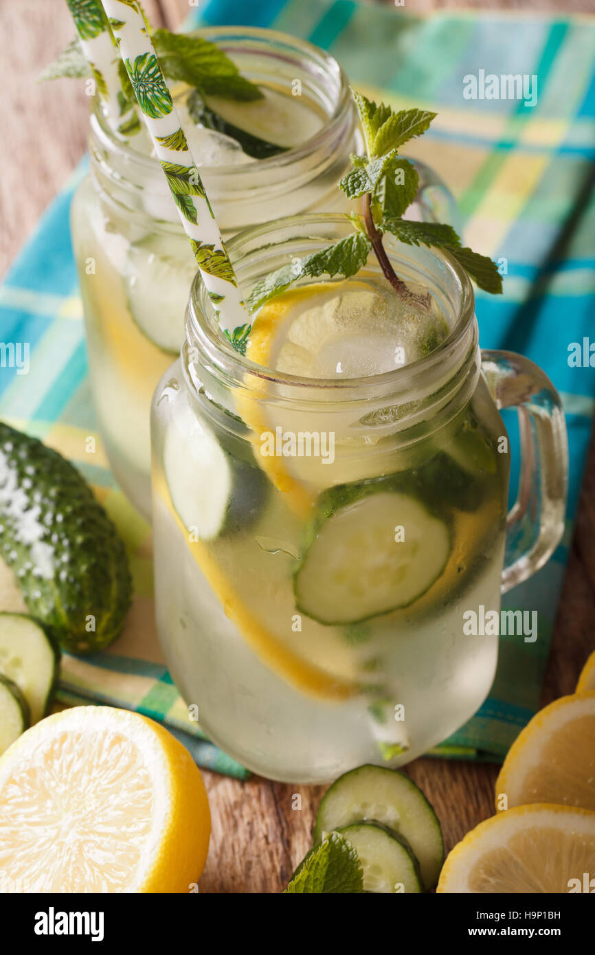 Copa de Verano con el pepino, limón, hielo y menta cerrar en un tarro de vidrio en la tabla vertical. Foto de stock