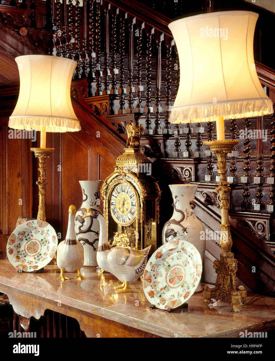 Vista parcial del salón interior en Antony House mostrando la mesa de mármol, gansos, reloj de cerámica, lámparas de mesa, jarrones y platos. Foto de stock
