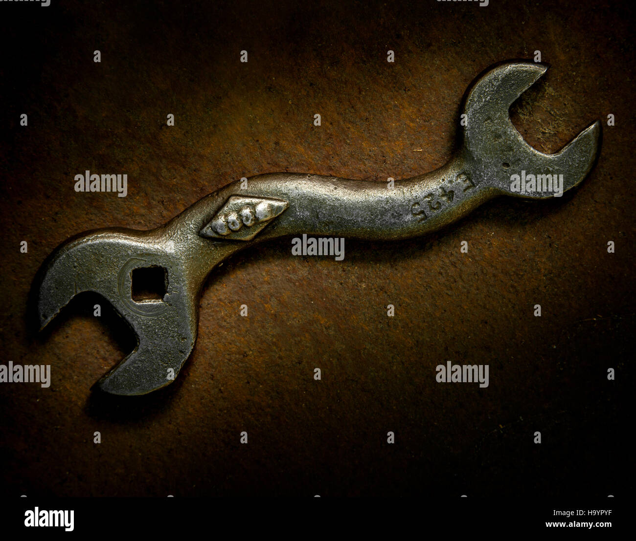 Fotografía usando luz Pintura de una vieja llave doblada sobre un fondo de metal oxidado. Foto de stock
