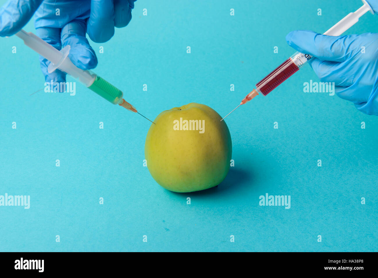 Los aditivos químicos en los alimentos modificados genéticamente o concepto  de fruta. Manzana Verde con jeringas de productos químicos. Aislado sobre  fondo azul Fotografía de stock - Alamy