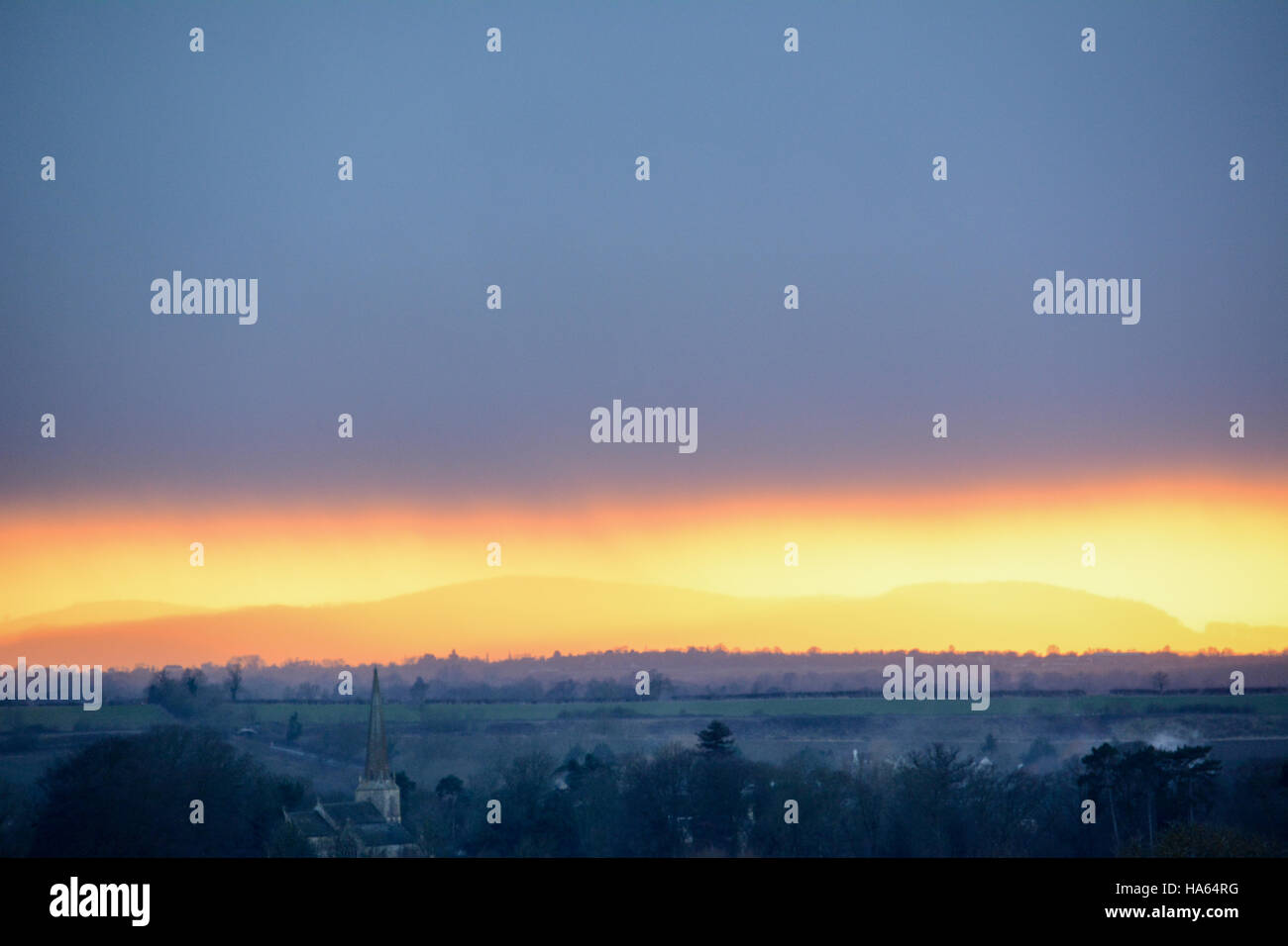 Tira de impresionante atardecer dorado capta Malvern Hills bajo el cielo gris pizarra con Vale de Evesham y Mickleton en primer plano Foto de stock