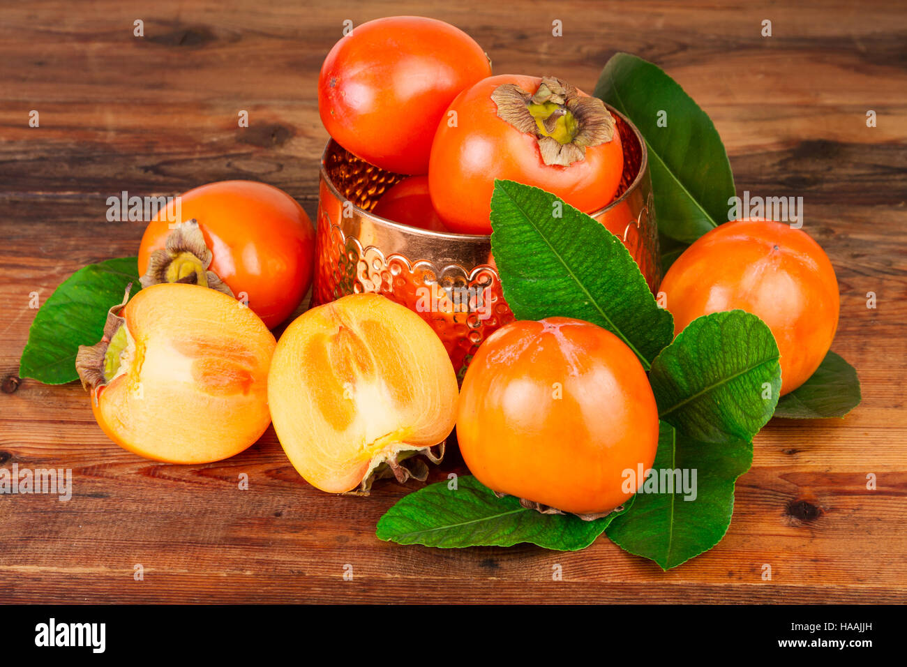 Caqui con vintage jarrón de cobre sobre madera vieja. Still life orientales. Foto de stock