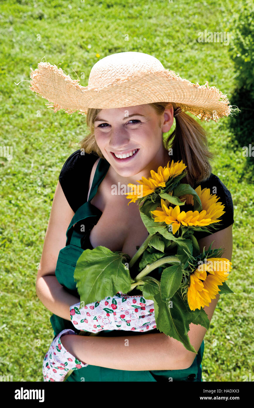 Chica con sombrero de paja y los girasoles Foto de stock