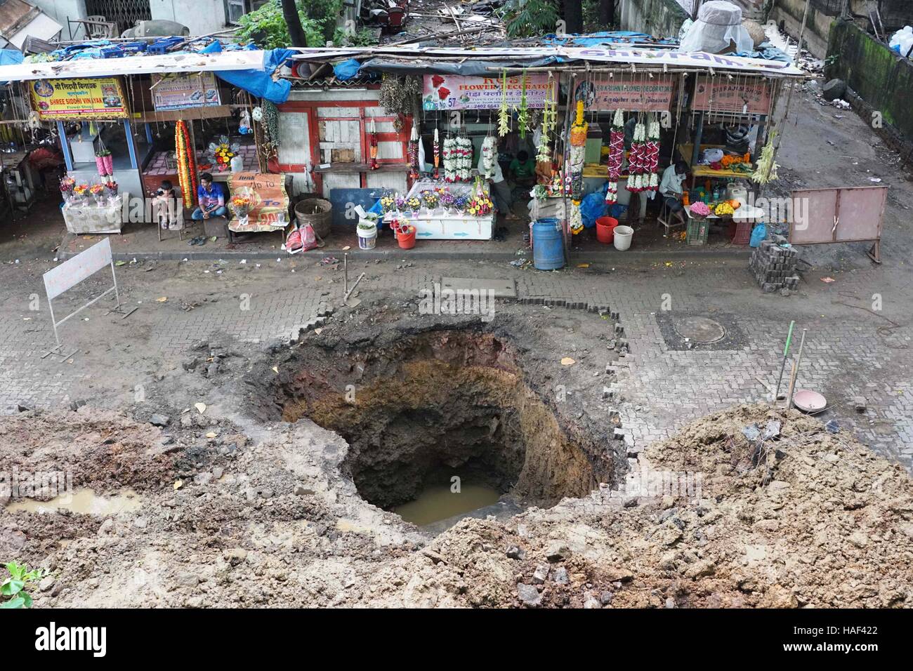 La superficie de la carretera se derrumba en Matunga, en Mumbai, India, el 24 de septiembre de 2016, para crear un sumidero tras un derrumbamiento. Foto de stock