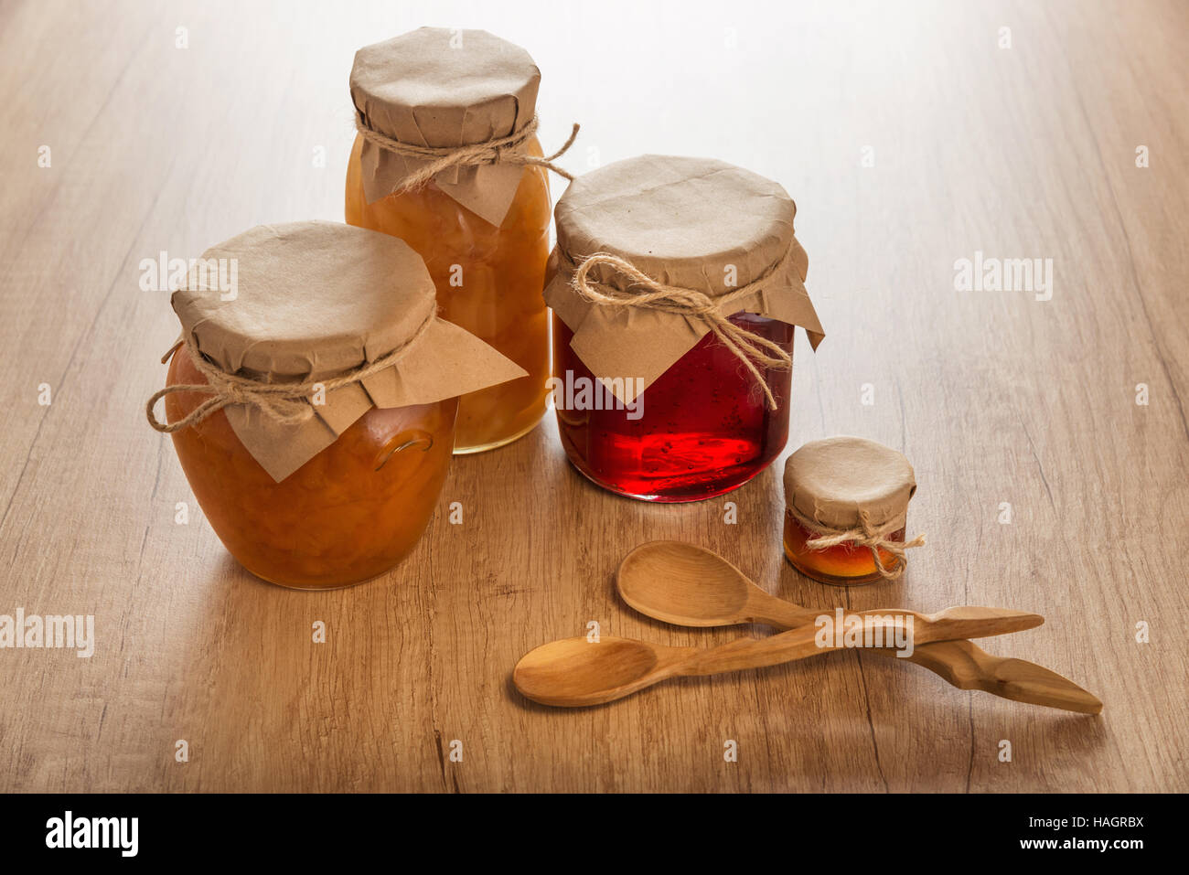 Dulce mermelada casera y cucharas sobre mesa de madera Foto de stock