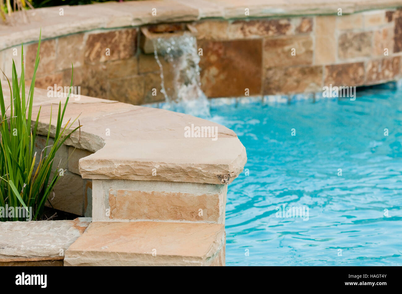 Hermosa piscina con cascada de pared de piedra laja que huye de ella  Fotografía de stock - Alamy
