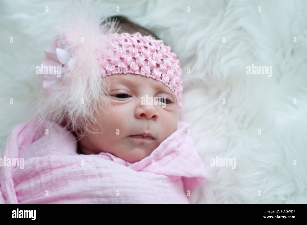 Bebé niña en Diadema rosa poniendo en piel blanca. Foto de stock