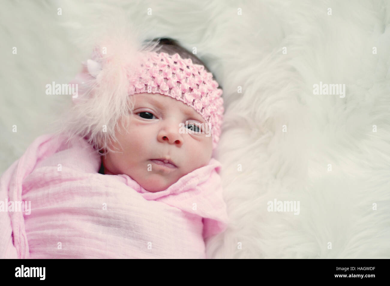 Bebé niña en Diadema rosa poniendo en piel blanca. Foto de stock
