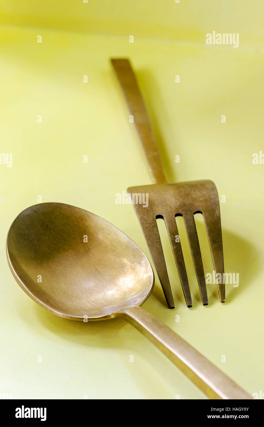Cuchara y tenedor de bronce antiguo sobre fondo amarillo,soft focus  Fotografía de stock - Alamy