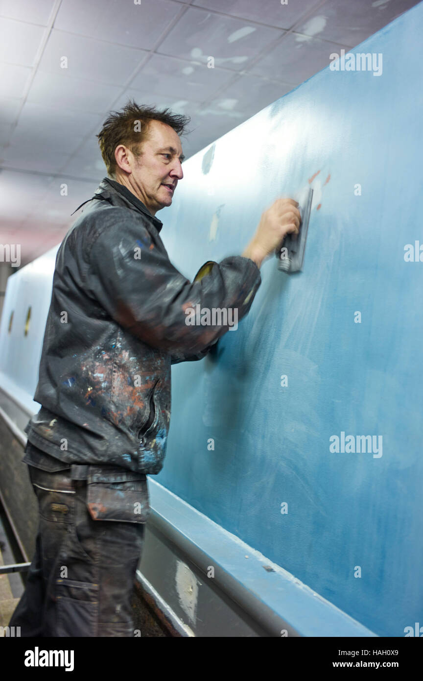 Andy Russell narrowboat pintor en el trabajo alisado subcapa en un narrowboat Foto de stock