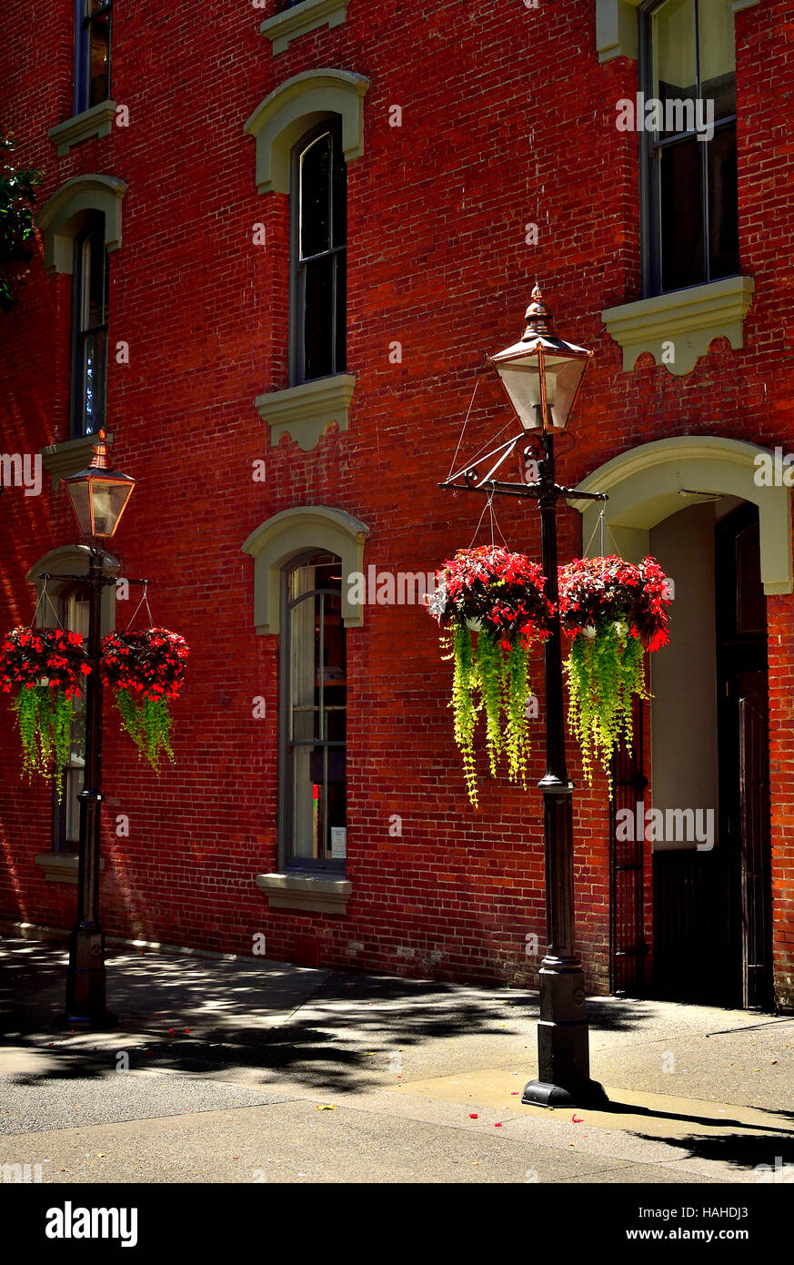 Las luces de la calle con cestas de flores en frente de un edificio de ladrillo Foto de stock