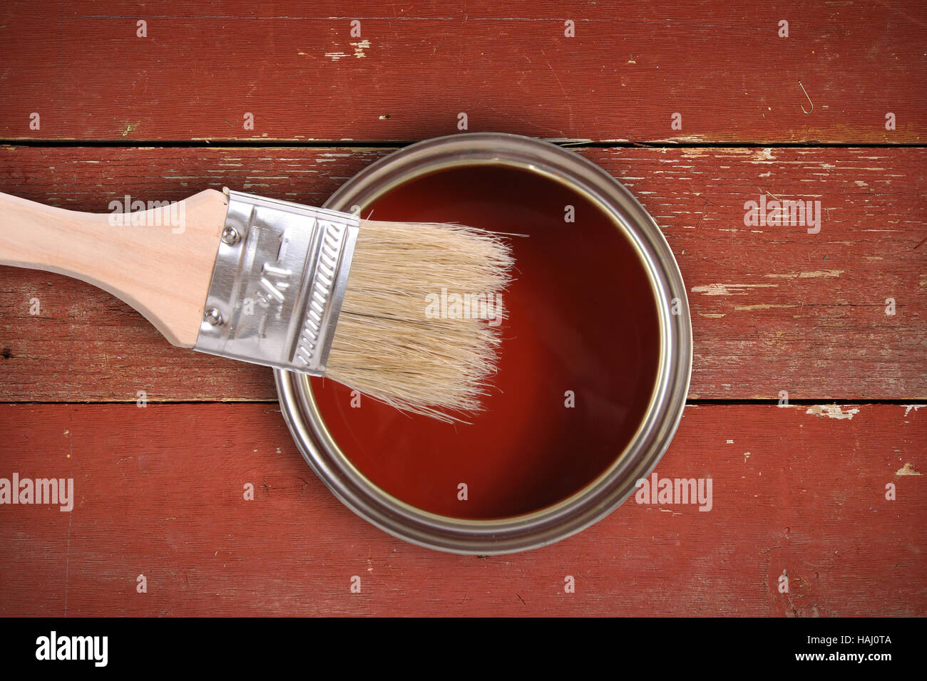 Lata de pintura roja con pincel sobre la plancha de madera antecedentes Foto de stock