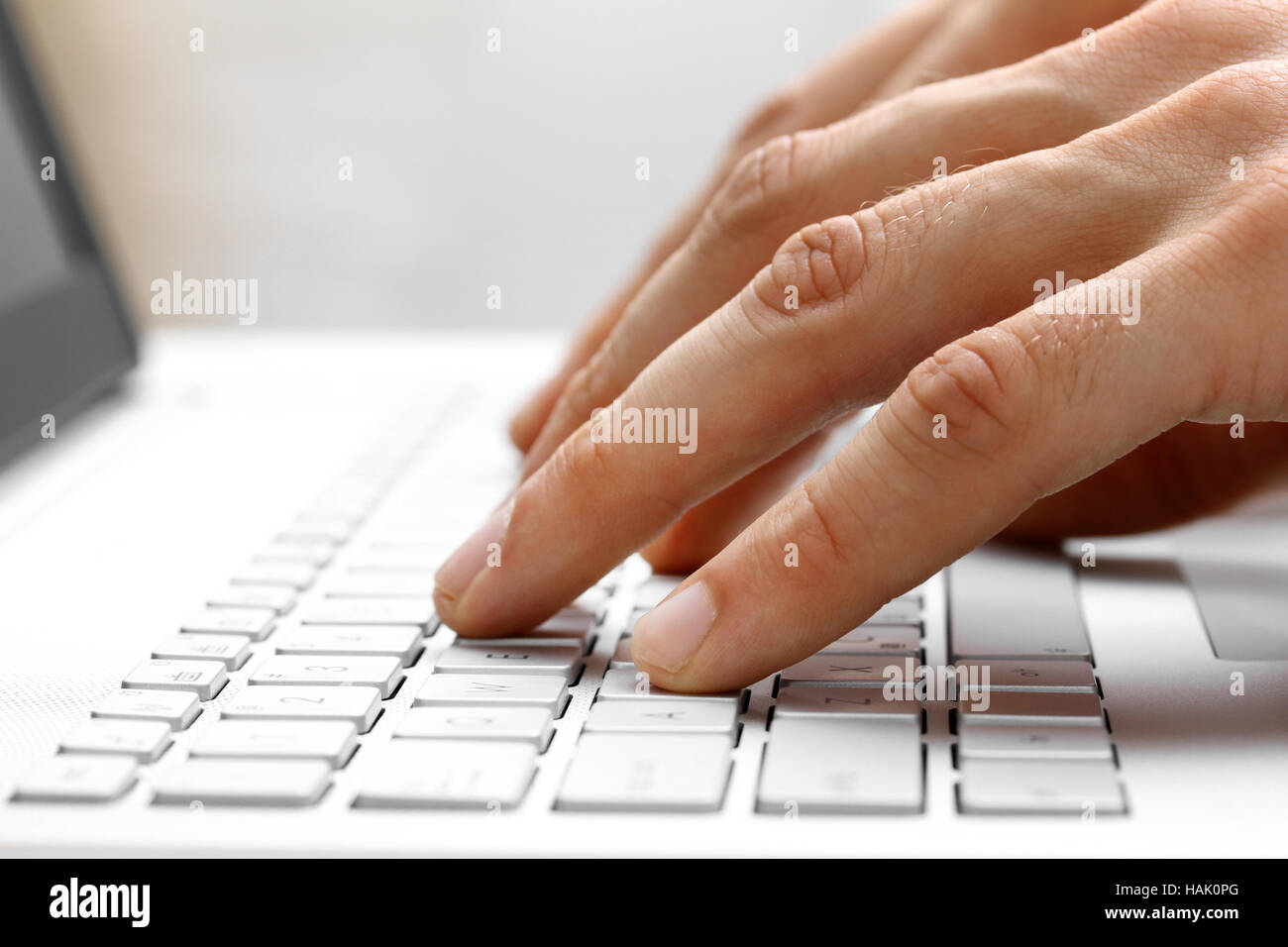 Dedos escribiendo en el teclado del ordenador portátil blanco Foto de stock