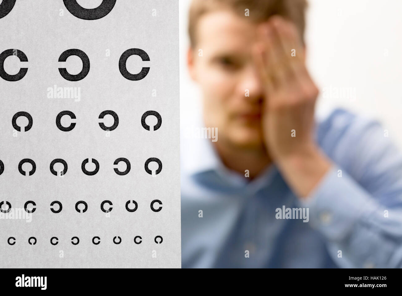 Vista comprobación. Paciente varón bajo examen de la visión del ojo se centran en gráfico de prueba. Foto de stock