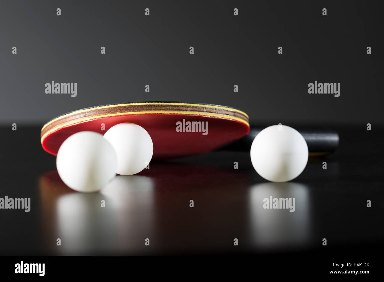 Raqueta y pelotas de tenis de mesa en mesa oscura Foto de stock