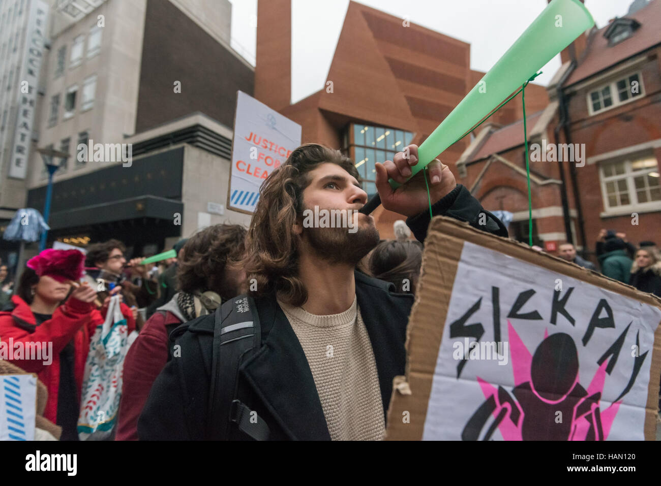 Londres, Reino Unido. 2 de diciembre de 2016. Un hombre sopla un cuerno de  plástico y tiene un cartel pidiendo indemnización por enfermedad en  protesta por la unión del limpiador de las