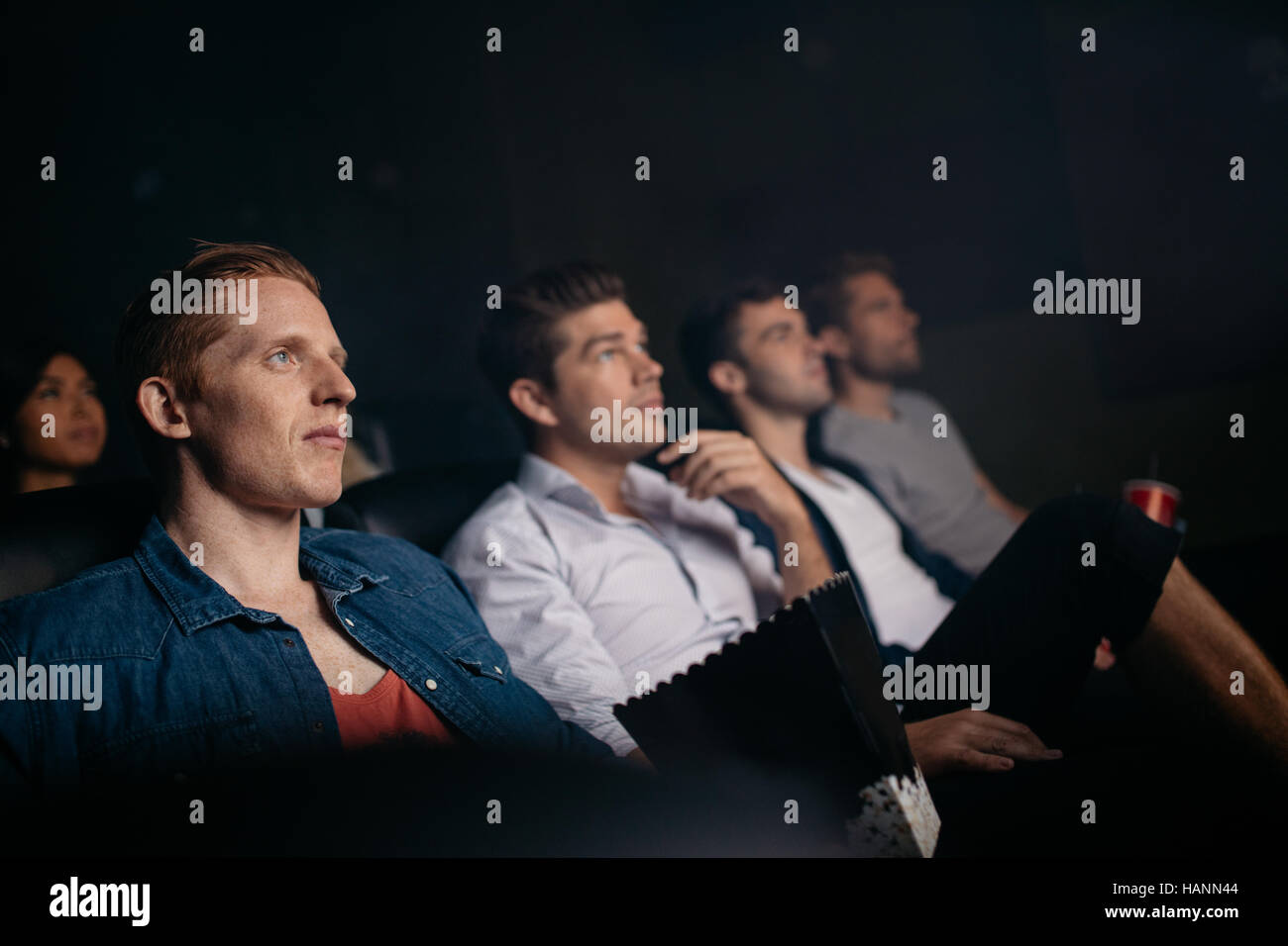 Grupo de gente sentada en el cine multiplex. Jóvenes amigos viendo la película en la sala de cine. Foto de stock