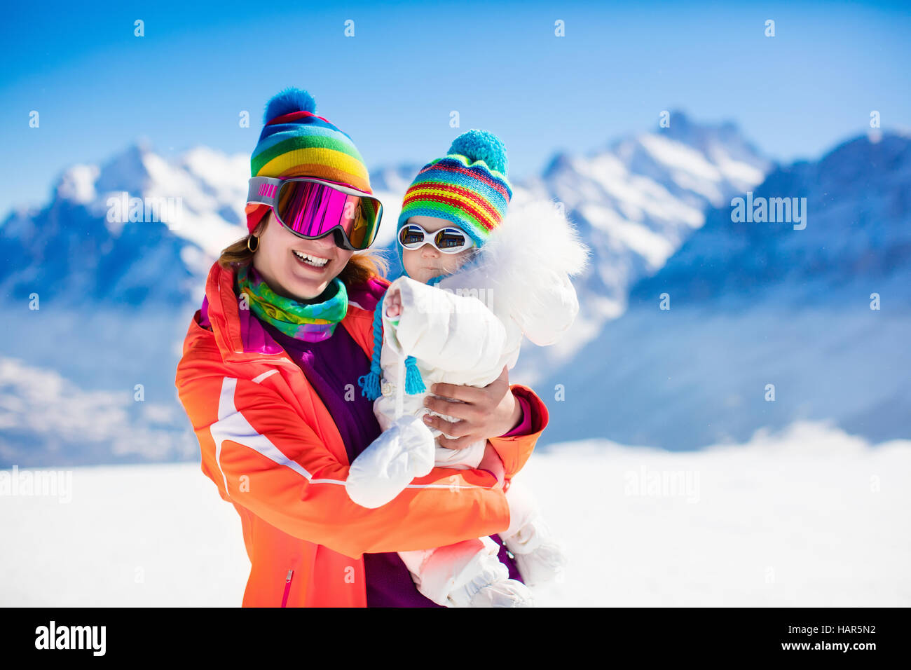 La joven madre y bebé disfruta de vacaciones de esquí en invierno