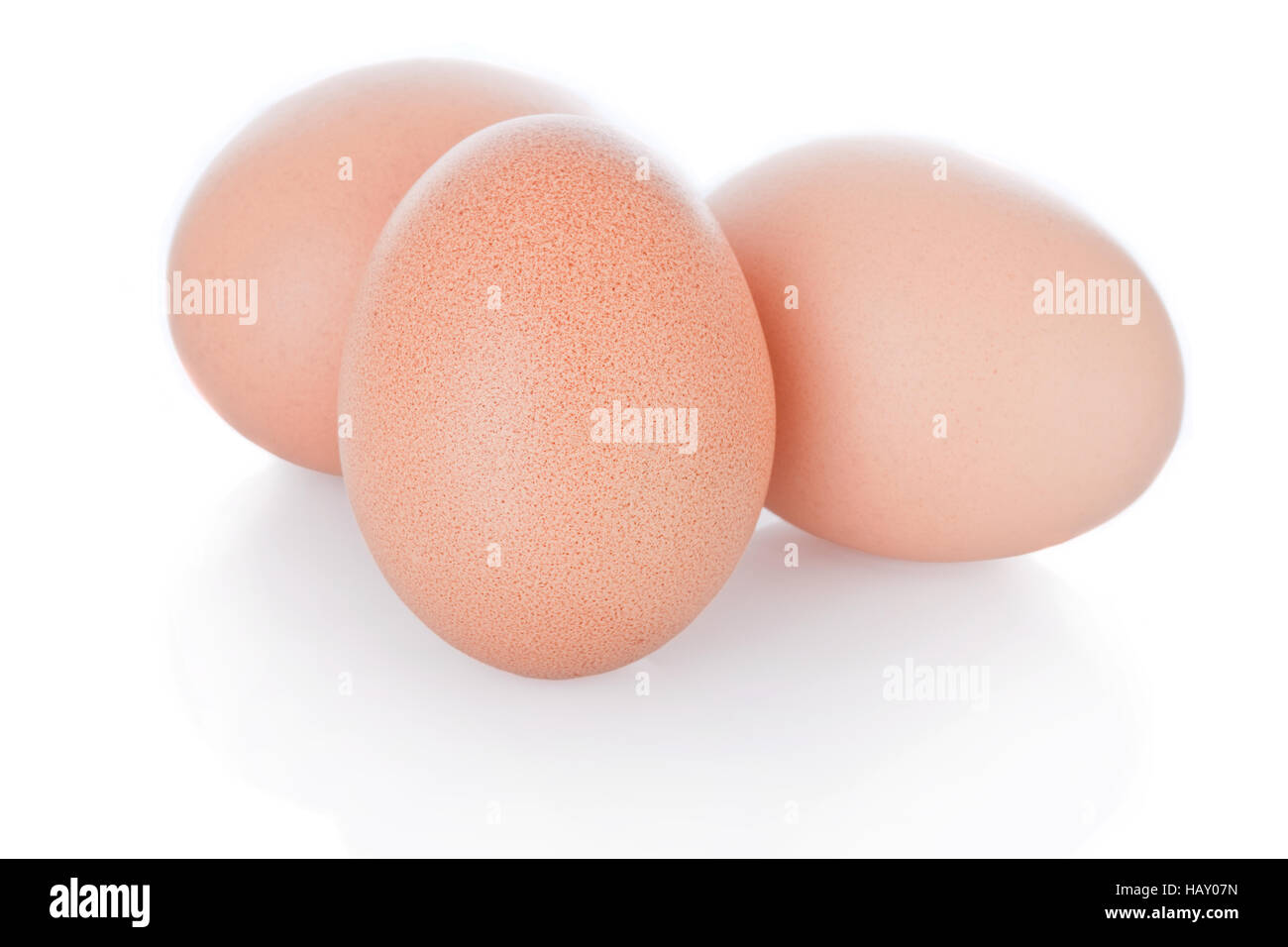 Tres huevos de gallina marrón aislado sobre fondo blanco. Foto de stock