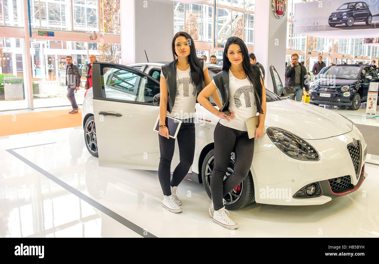 Bolonia, Italia, Dec 03 2016 - Dos modelos morena posando recostada a un Alfa Romeo blanco Giulietta Fiat Auto en el stand del Motorshow 2016 en Bolog Foto de stock