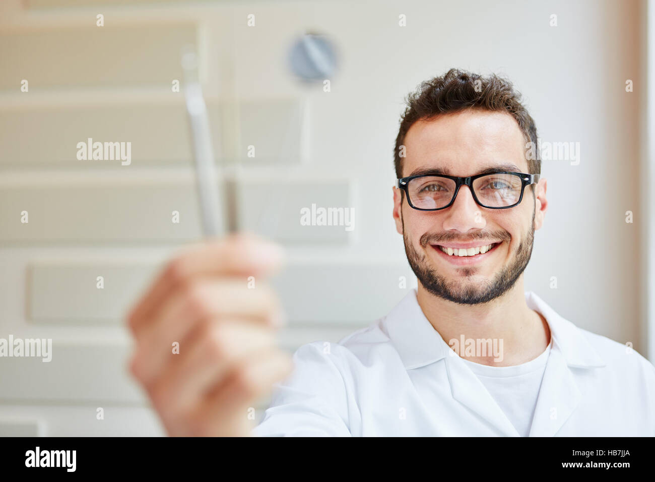 El hombre como enfermera dental la celebración de diferentes herramientas en su mano Foto de stock