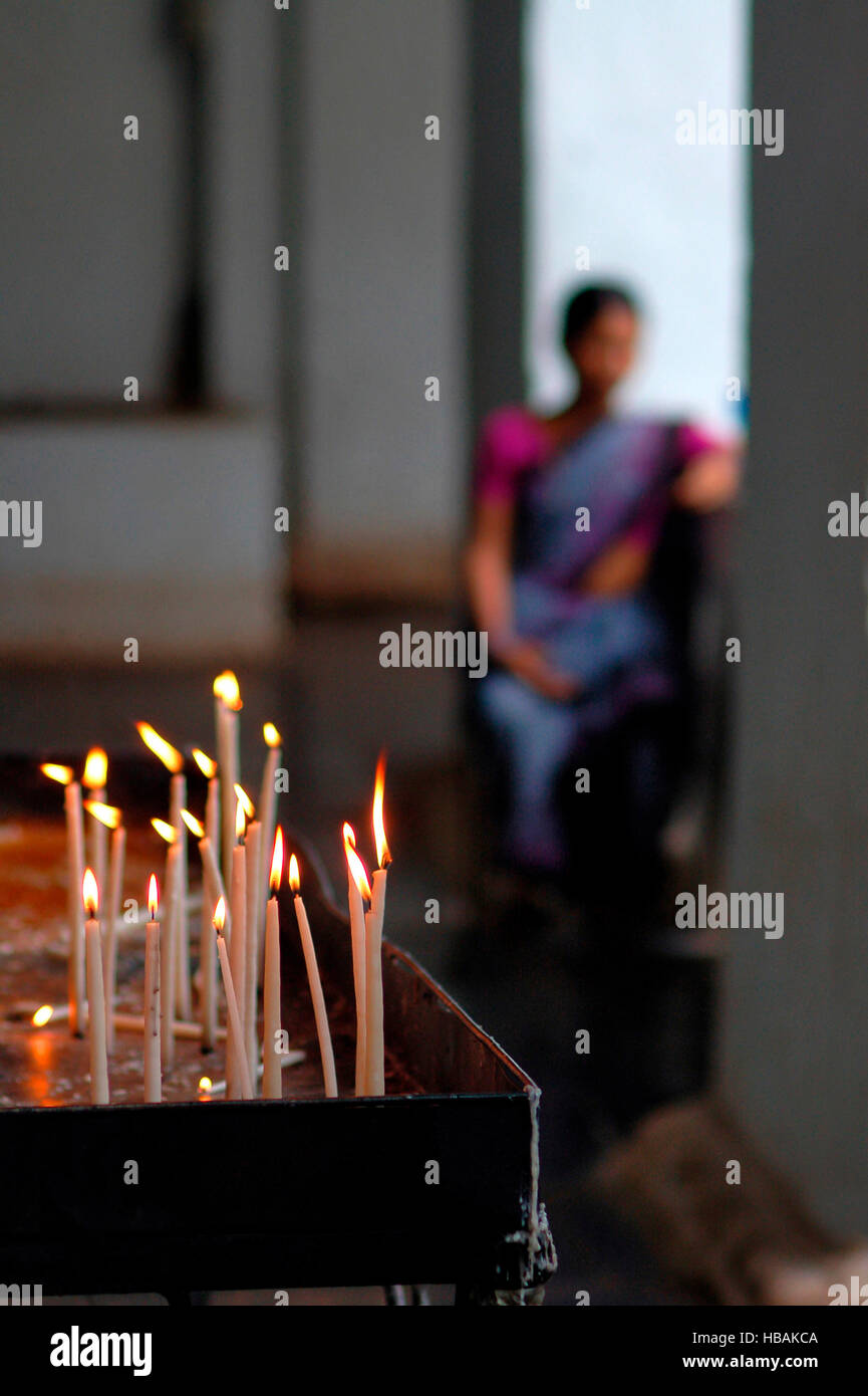 Velas votivas o velas de oración como ofrenda a Dios. Mujer al fondo. sawantwadi iglesia, Maharashtra, India Foto de stock