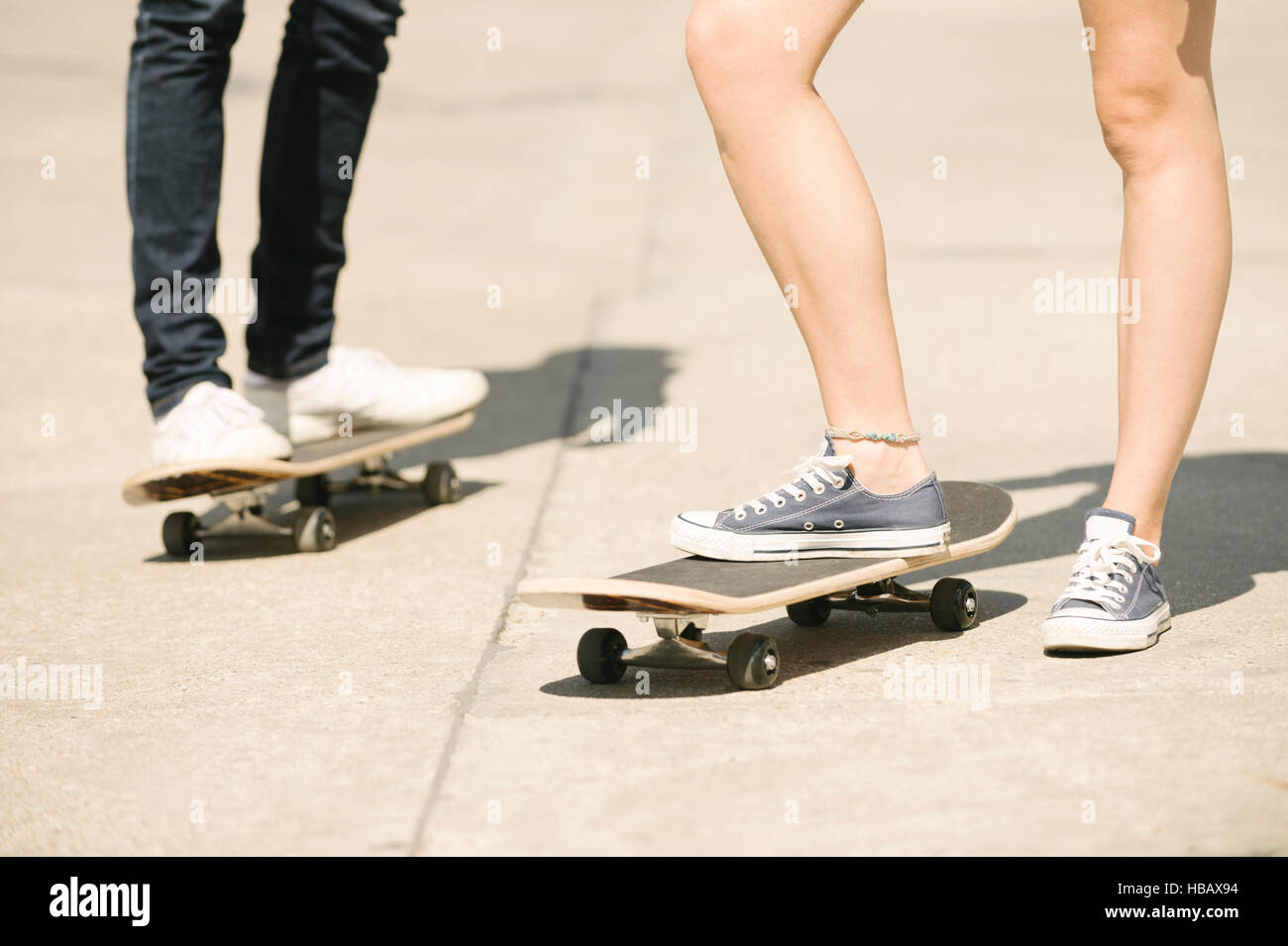 Patas de macho y hembra skateboarders de pie en skatepark Foto de stock