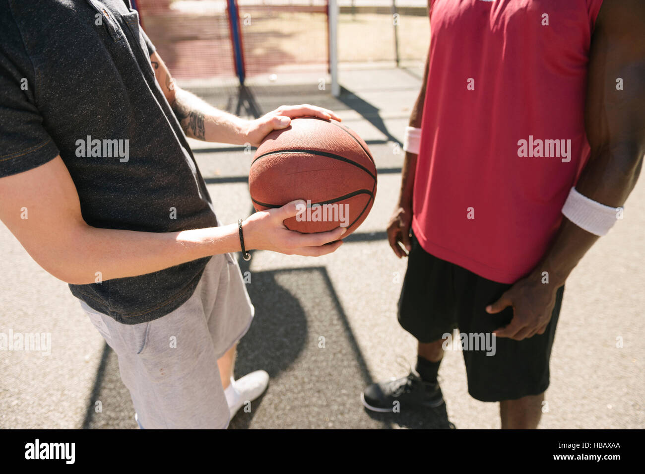 Sección intermedia de dos jugadores de baloncesto masculino con la bola en la cancha de baloncesto Foto de stock