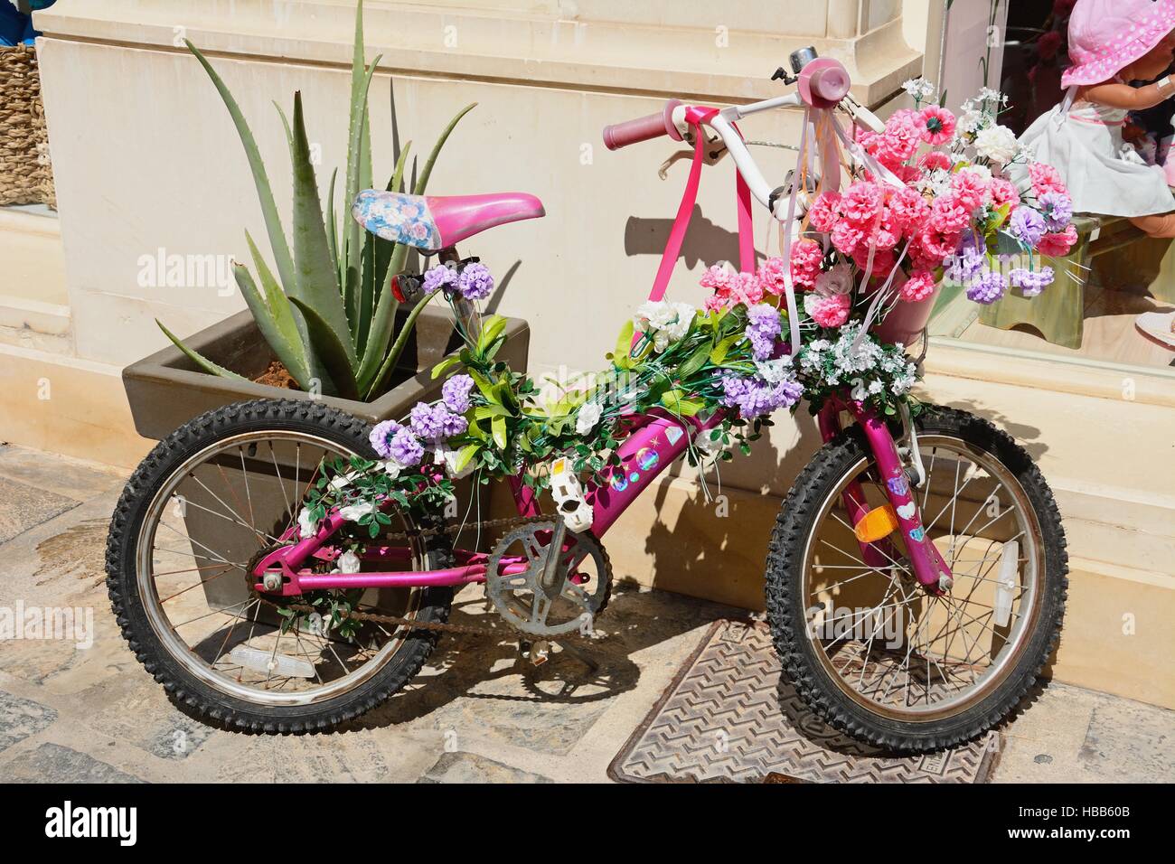 Las niñas rosa decorada con flores en bicicleta a lo largo de una calle de  tiendas en el casco antiguo de la ciudad de Rethymno, Creta, Grecia, Europa  Fotografía de stock -