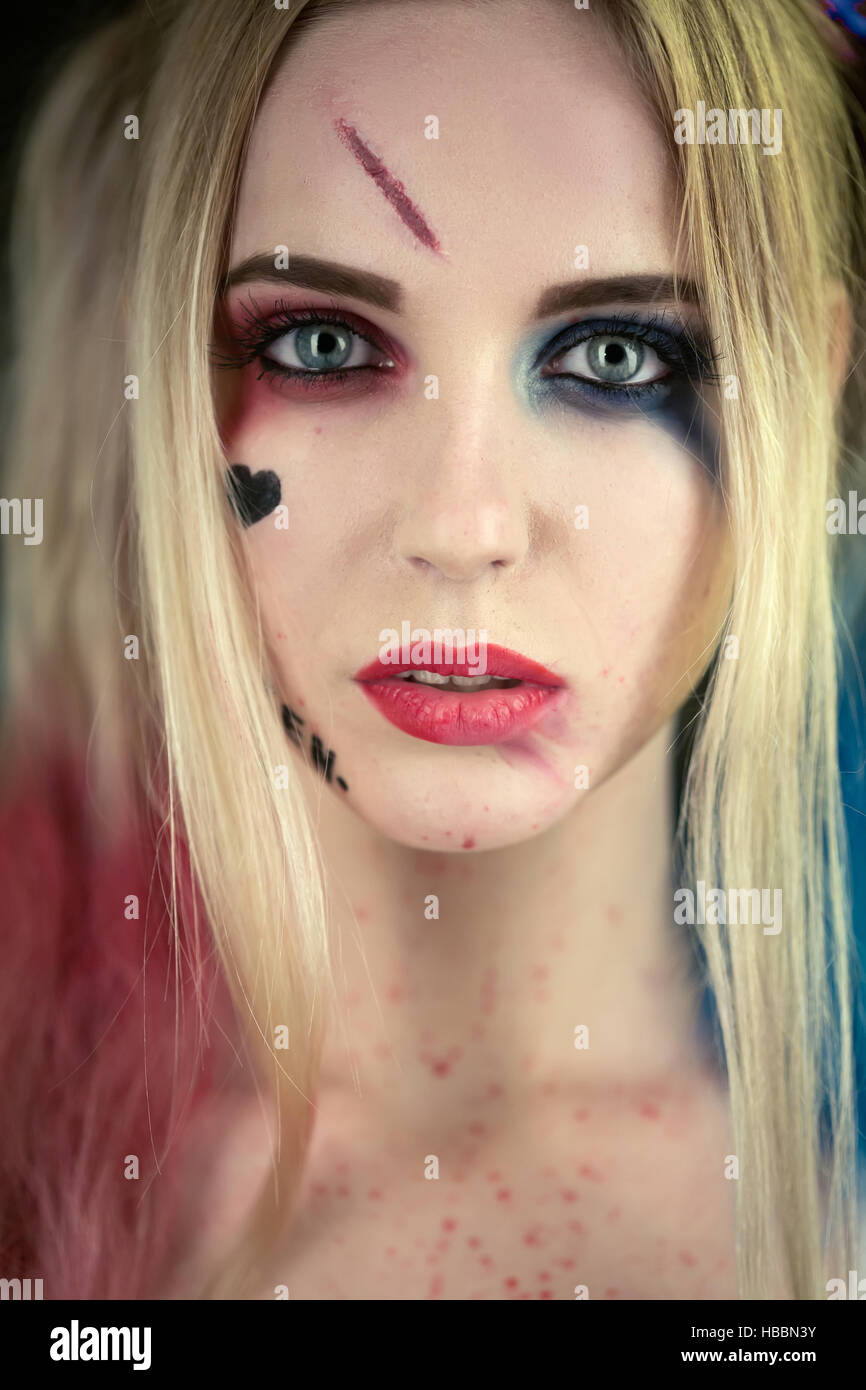 Chica en traje de Harley Quinn. Ella se levanta con un bate y lame el bat.  Cerca. Cosplay Fotografía de stock - Alamy