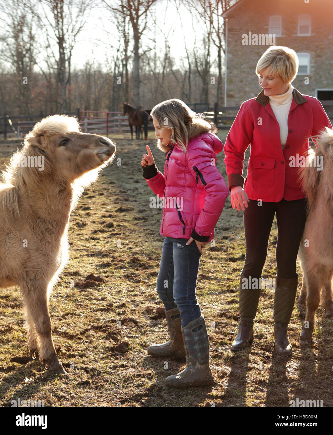 Madre e hija afuera, hija dando instrucciones al pony Foto de stock