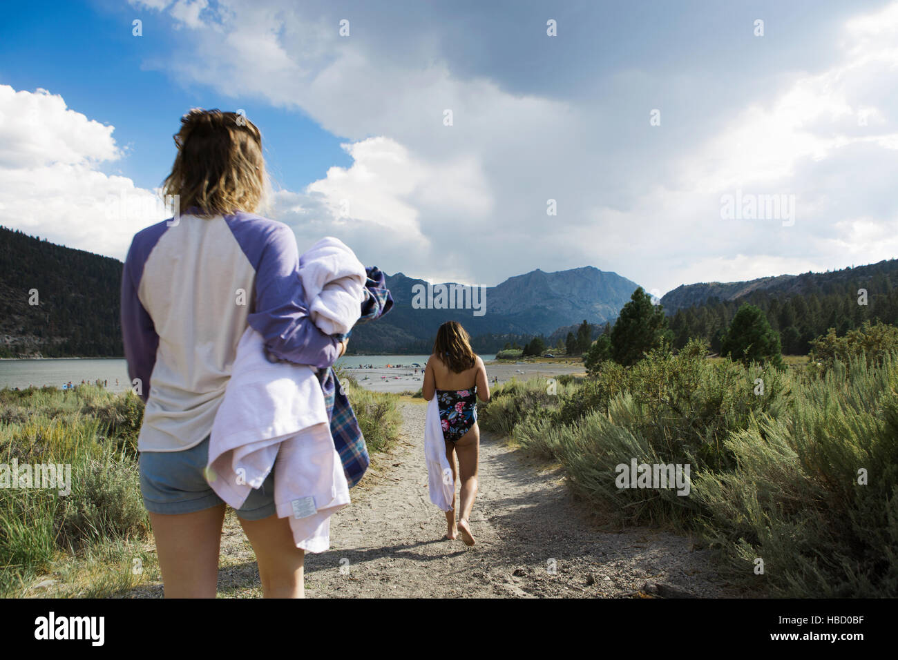 Vista trasera de dos mujeres jóvenes paseando al lago llevar toallas, Mammoth Lakes, California, EE.UU. Foto de stock