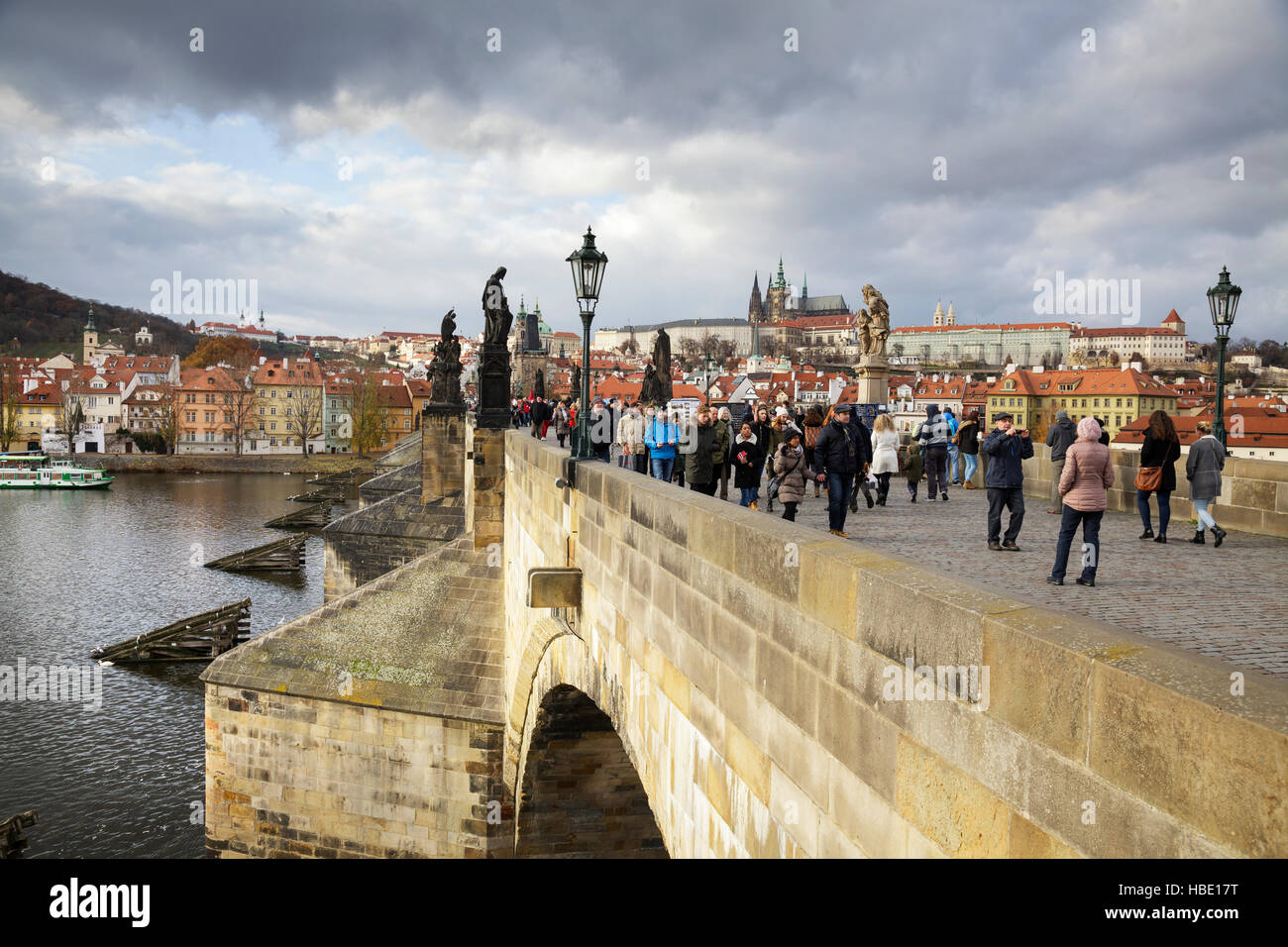Hay turistas que caminan por el Puente de Carlos bajo un cielo tormentoso, Praga, República Checa Foto de stock