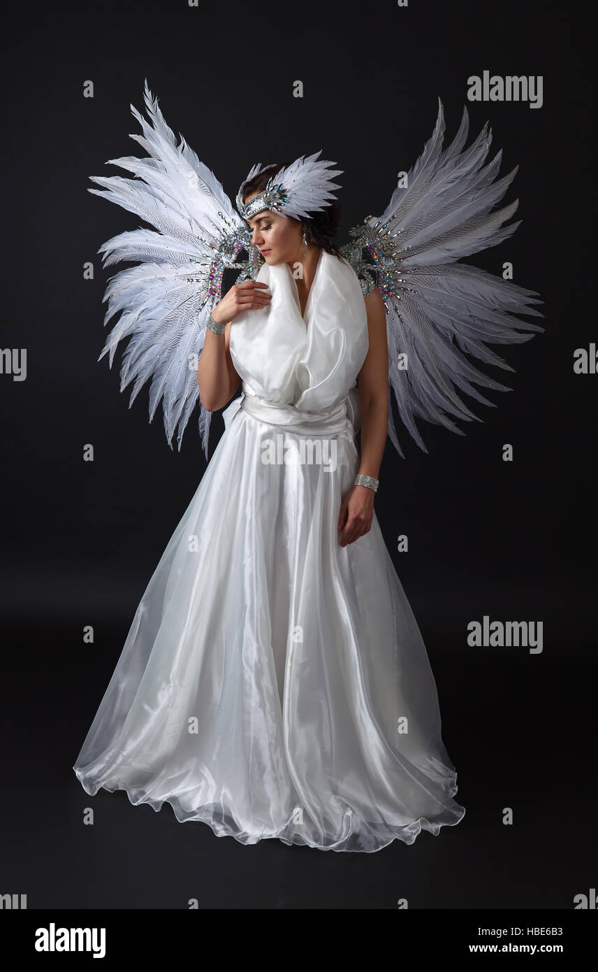 Hermosa mujer joven en vestido blanco con alas de ángel sobre fondo negro  Fotografía de stock - Alamy