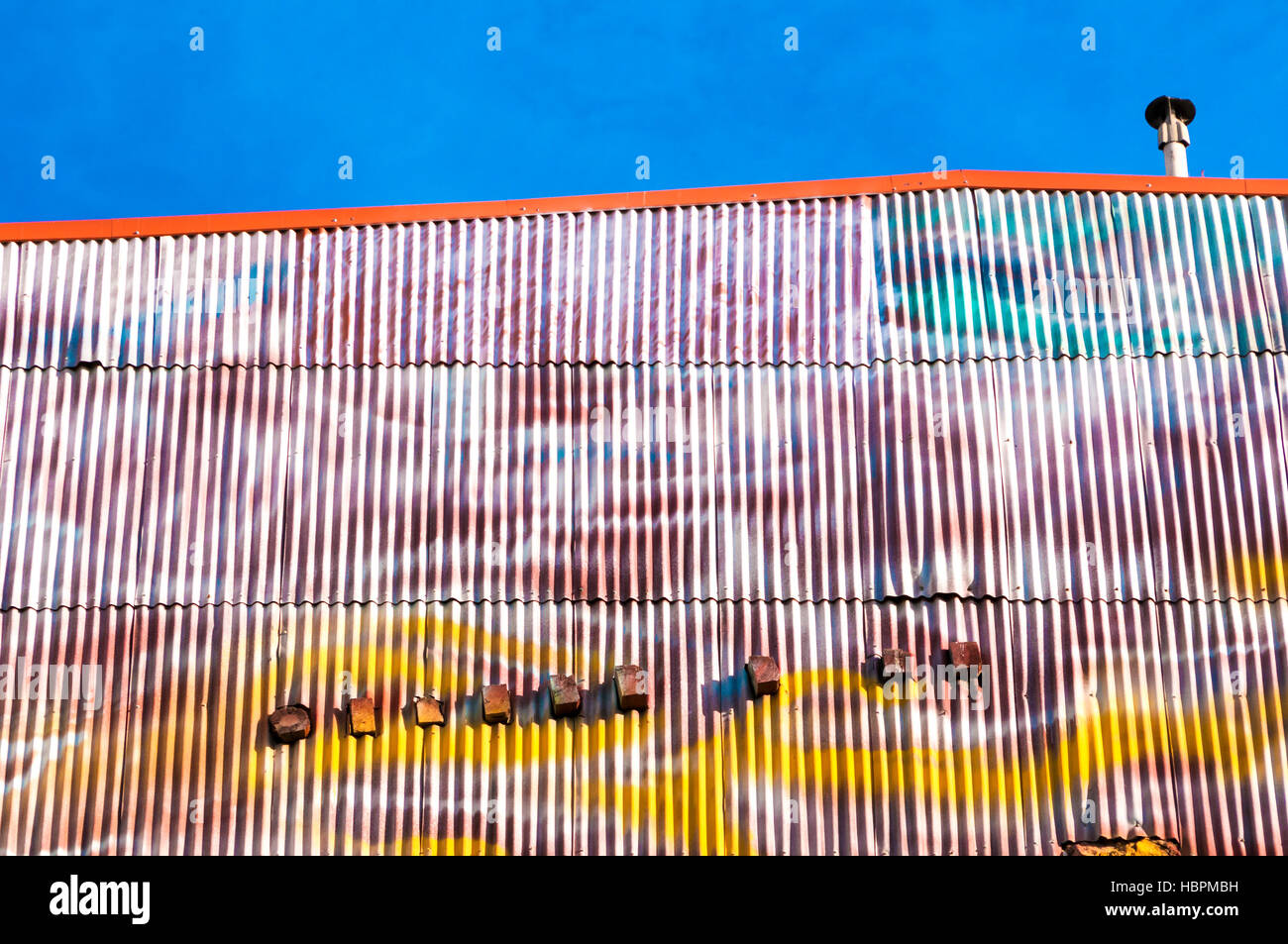 Gran grunge la pintura en la pared de un edificio industrial con cielo azul Foto de stock