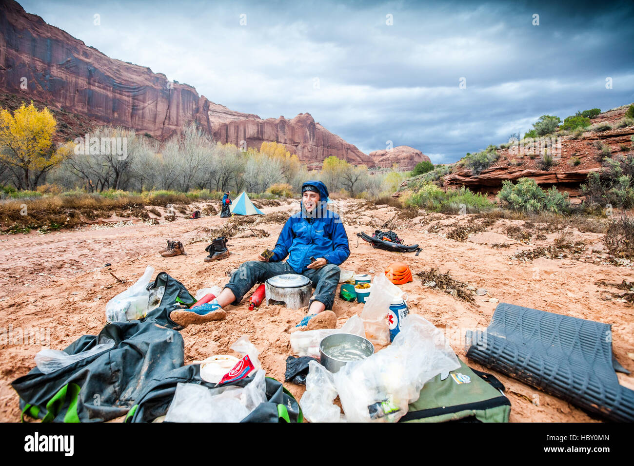 Un hombre joven en un camping de lavado en seco, cocinar la cena bajo una tormenta en los cañones de Utah Foto de stock