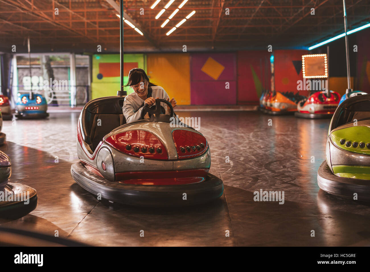 Feliz joven conduciendo un coche en el parque de diversiones de paragolpes Foto de stock