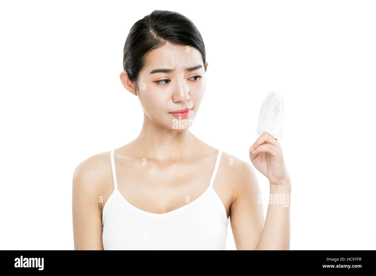 Retrato de joven mujer sosteniendo un algodón cosmético ceño fruncido Foto de stock