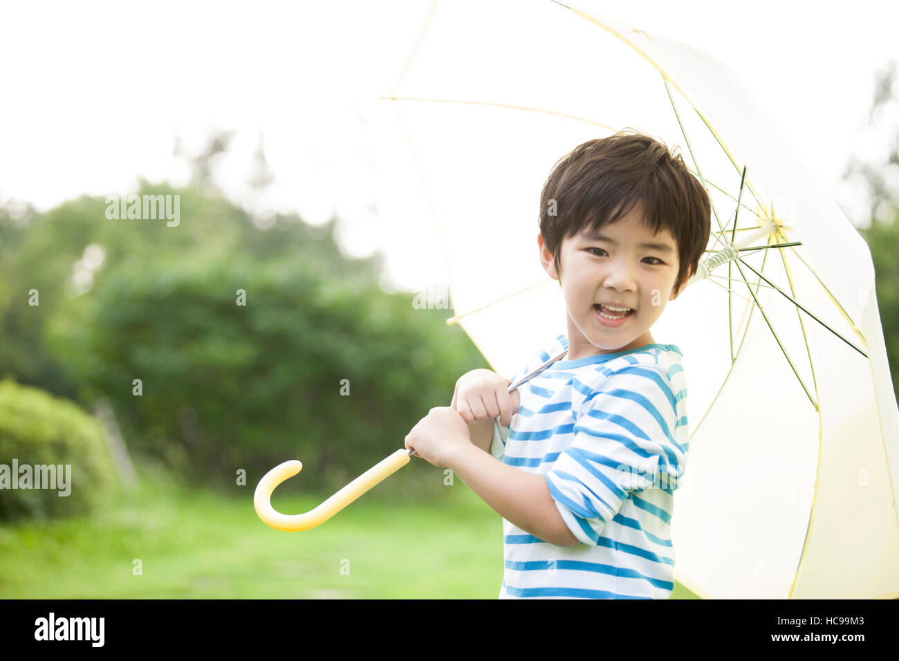 Retrato de niño sonriente sosteniendo paraguas en el campo Foto de stock