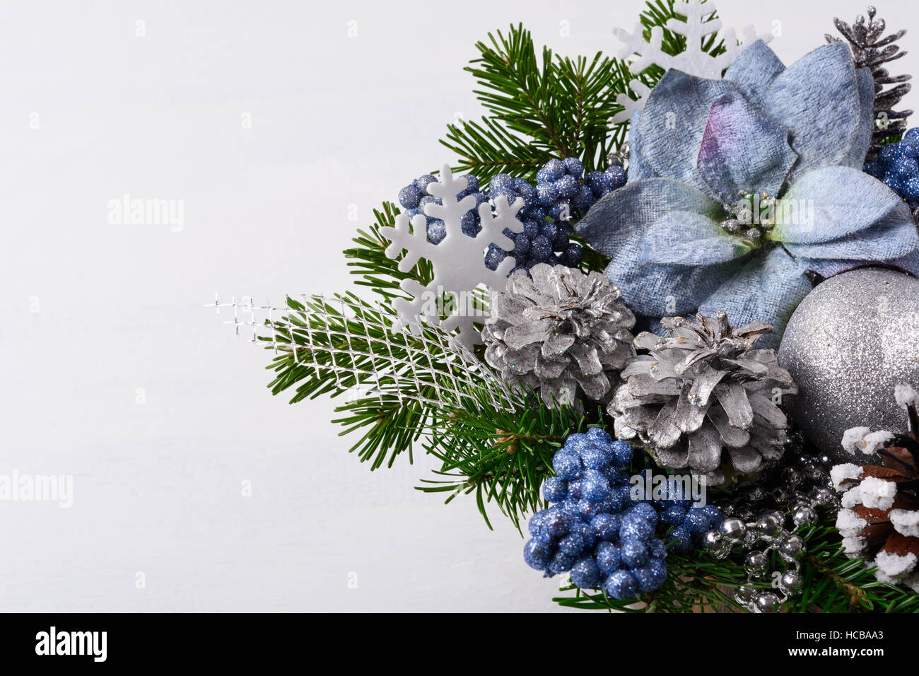 Decoración de navidad con copos de nieve artesanal de seda azul y la flor de  pascua. Arreglo de flores de navidad artificial con piñas y ramas de abeto.  Chr Fotografía de stock -