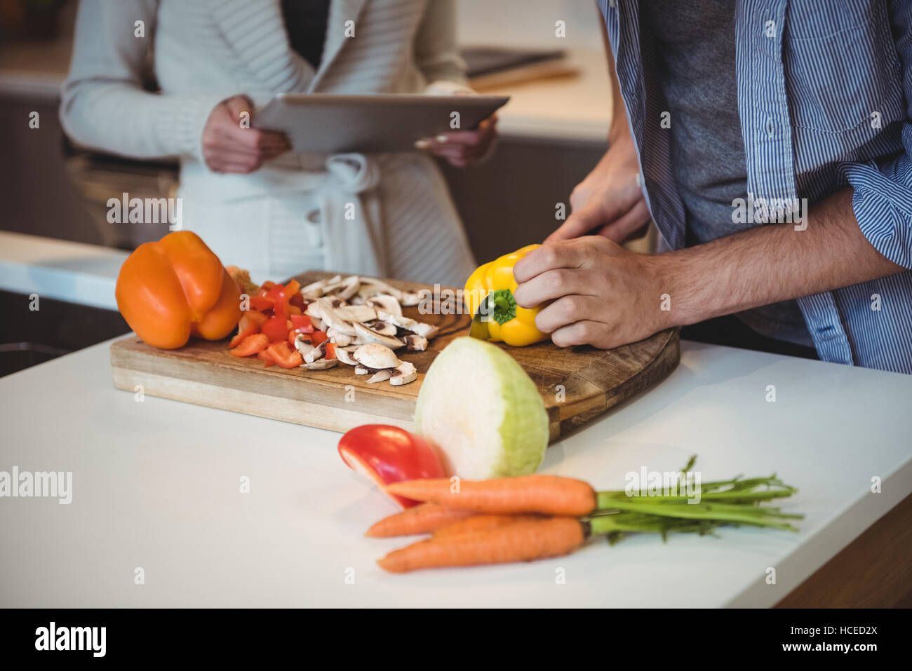 Pareja utilizando tablet digital mientras picar las verduras en la cocina Foto de stock