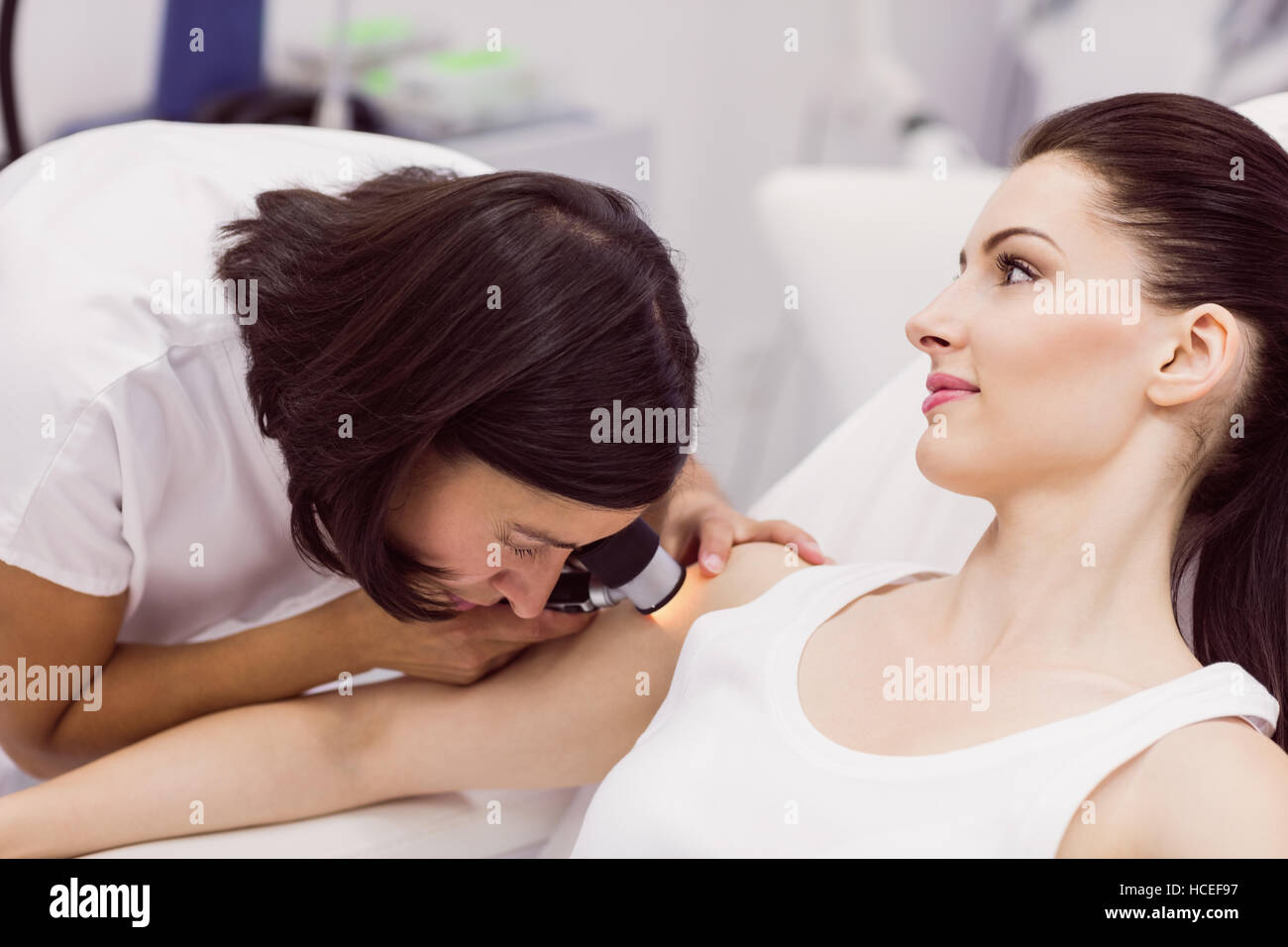 El dermatólogo examinar la piel del paciente con dermatoscope Foto de stock