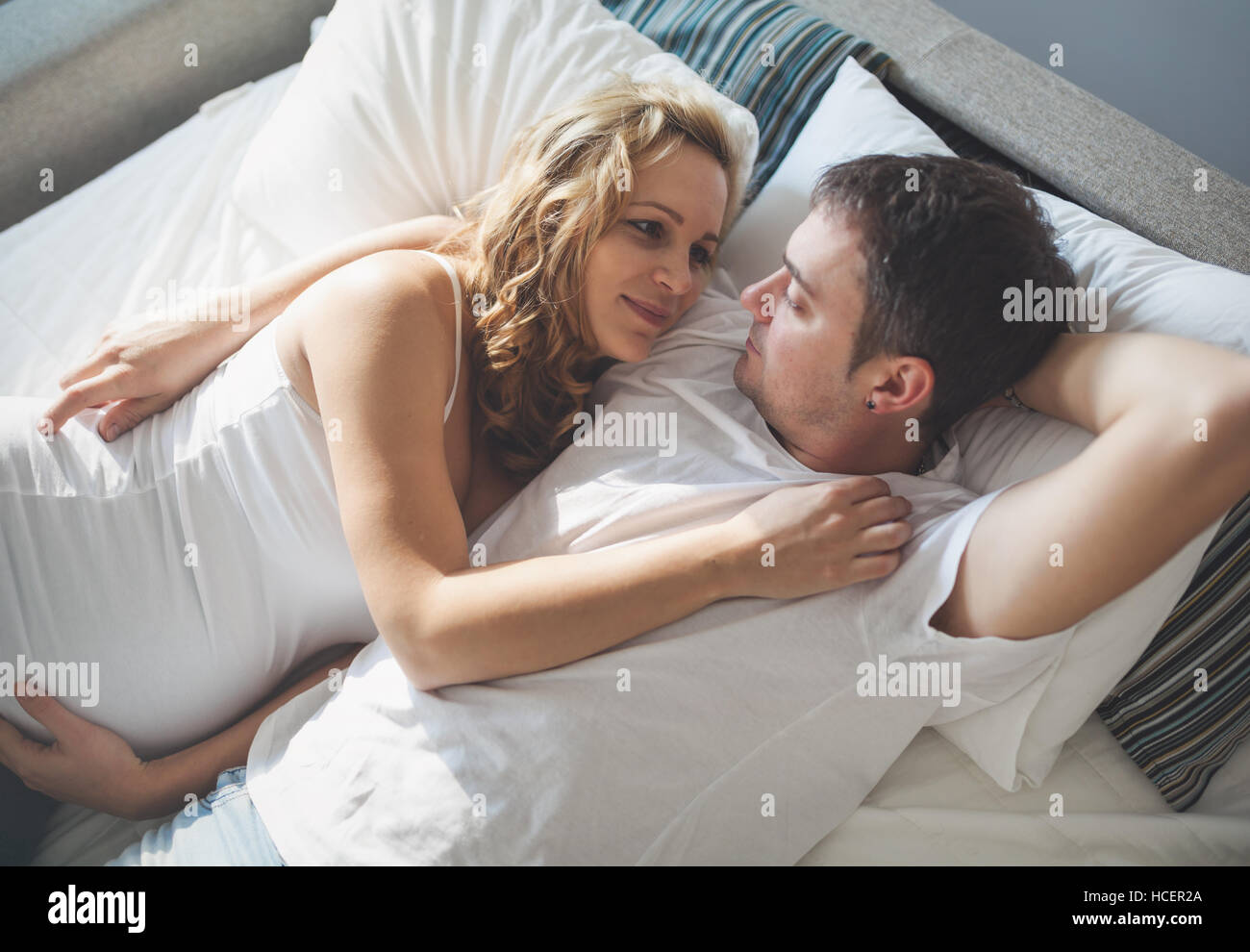 Feliz embarazada esposa acostado en la cama con mi marido Foto de stock