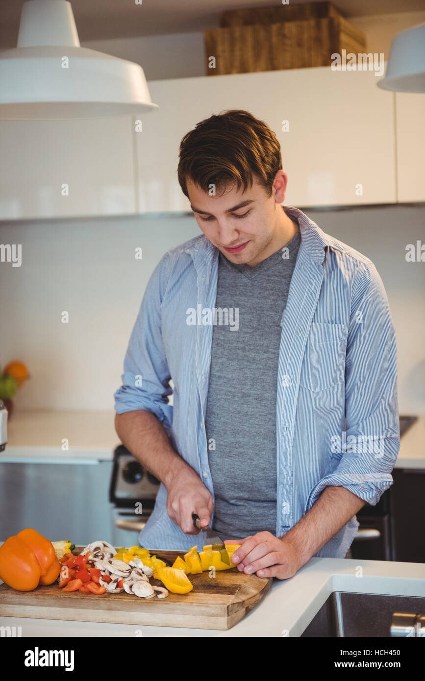 Hombre cortando verduras en la cocina Foto de stock