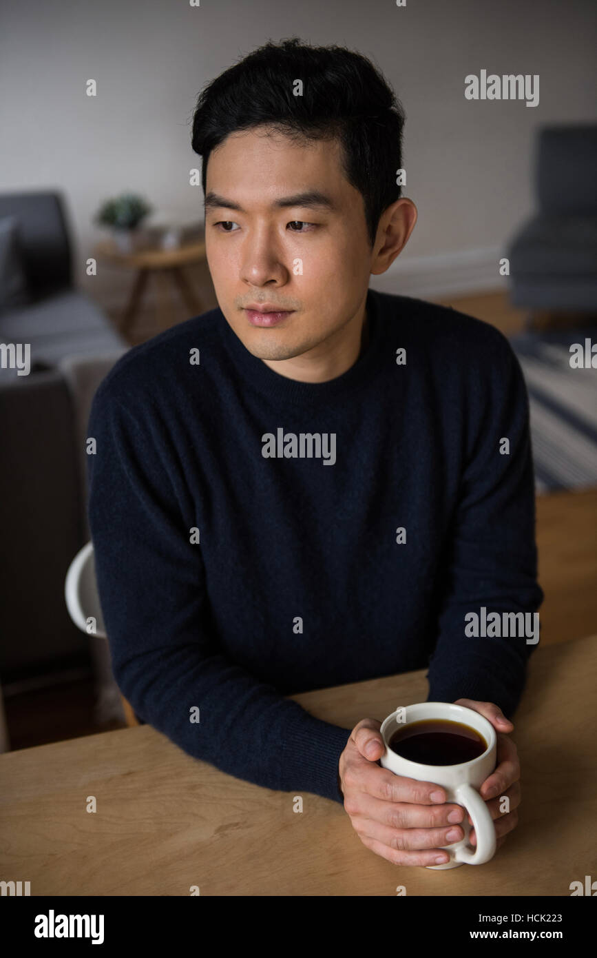 Pensativo hombre sujetando una taza de café negro Foto de stock