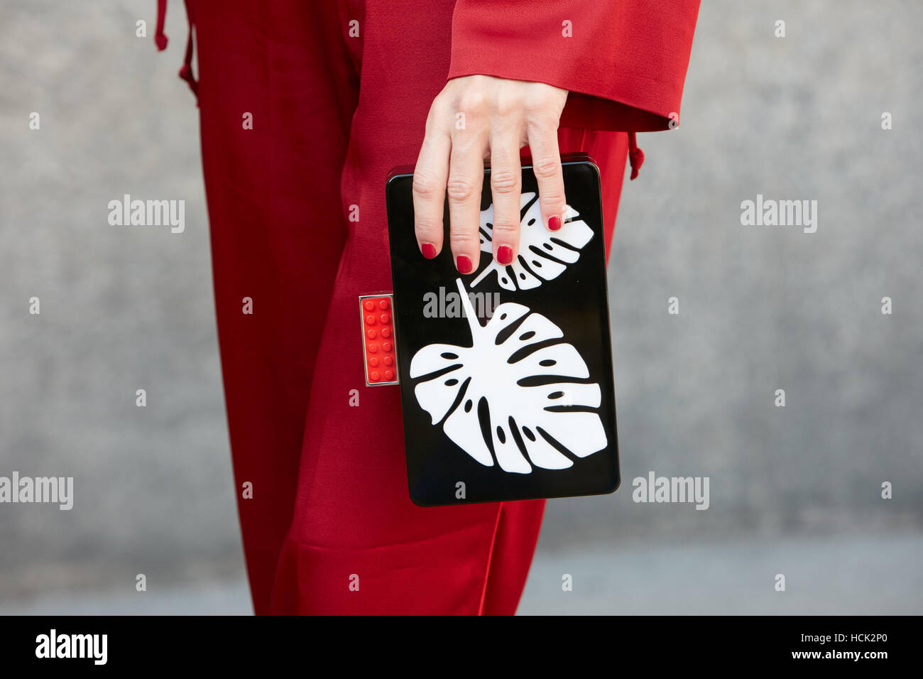 Mujer con bolsa negra con hojas en blanco y rojo diseño Lego detalle antes de Salvatore Ferragamo Fashion Show, la Semana de la moda de Milán. Foto de stock