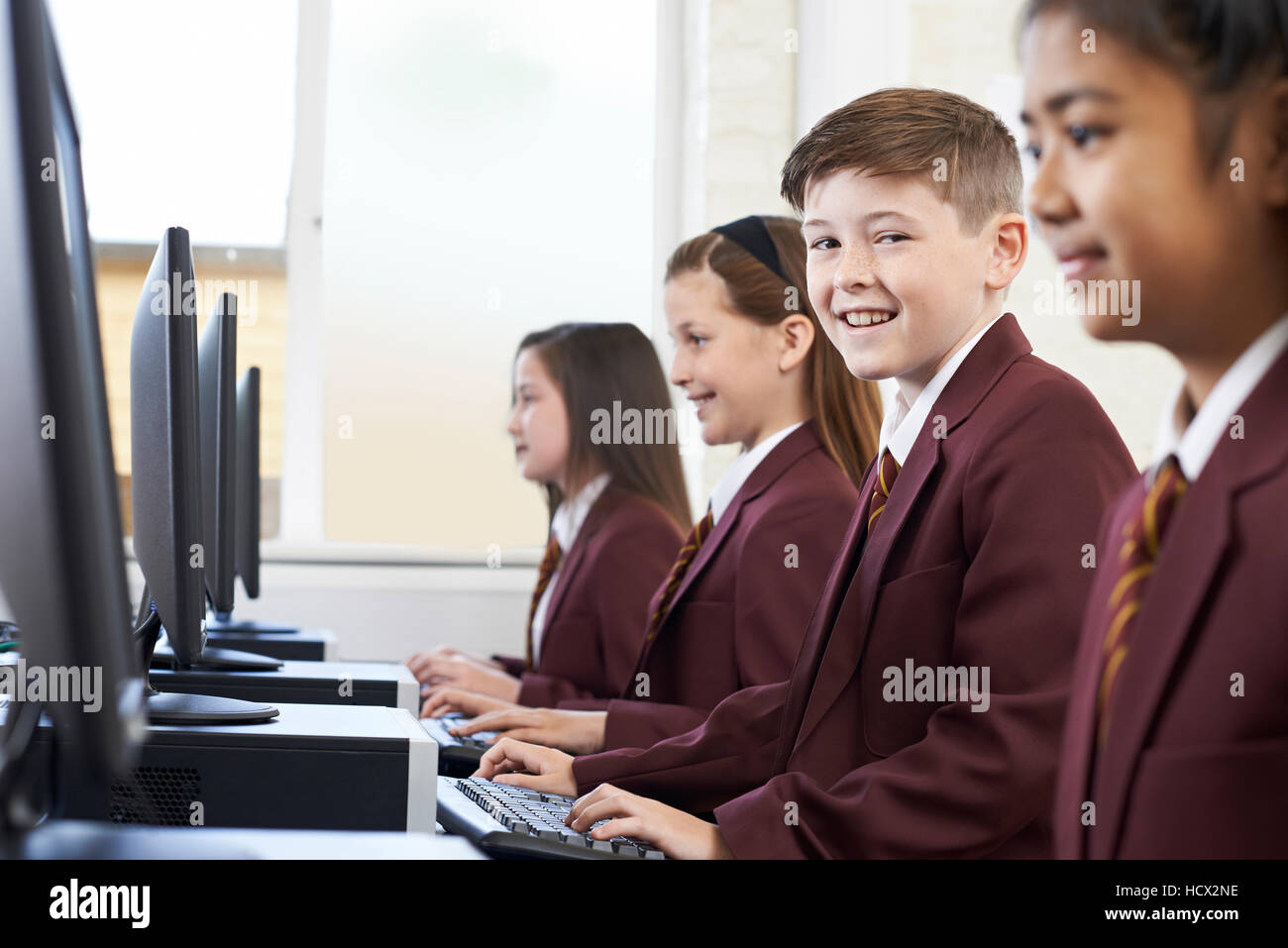 Los alumnos vistiendo uniforme escolar en clase de computación Foto de stock