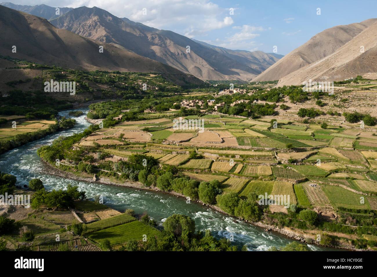 El verde de los campos irrigados contrasta con las áridas colinas, Afganistán Foto de stock