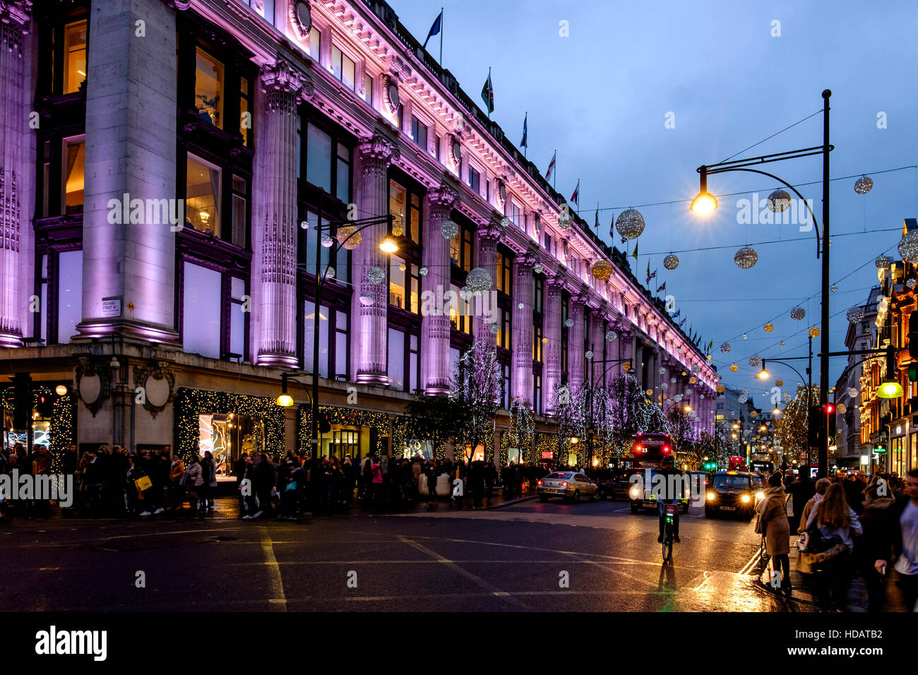 Londres, Reino Unido. 10 dic, 2016. Compras de Navidad en West End en Londres el 10/12/2016 por Oxford Street , . Selfridges está iluminado en color rosa, reflejándose en la húmedo, ocupado como compradores de Oxford Street y el tráfico pasa. Crédito: Julie Edwards/Alamy Live News Foto de stock
